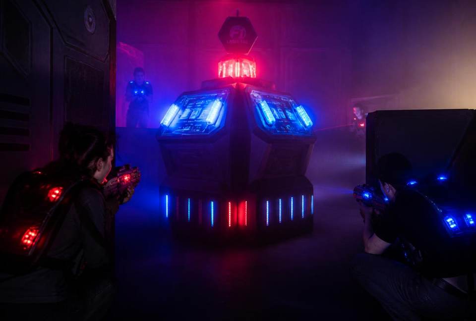 Base lumineuse de laser tag défendue par deux joueurs accroupis dans le brouillard